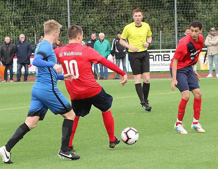 Ein Schiedsrichter begleitet eine Spielszene auf dem Fußballplatz